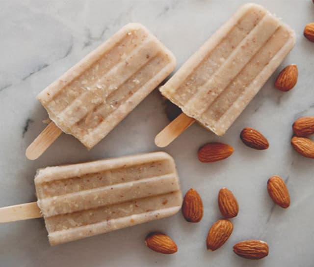 Three coconut almond milk ice pops next to Blue Diamond Toasted Coconut Almonds
